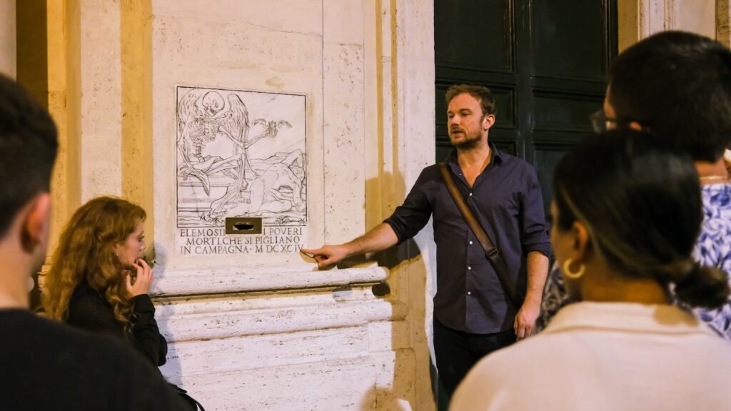 Guide pointing to a wall plaque while guests listen on a Rome ghost tour at night
